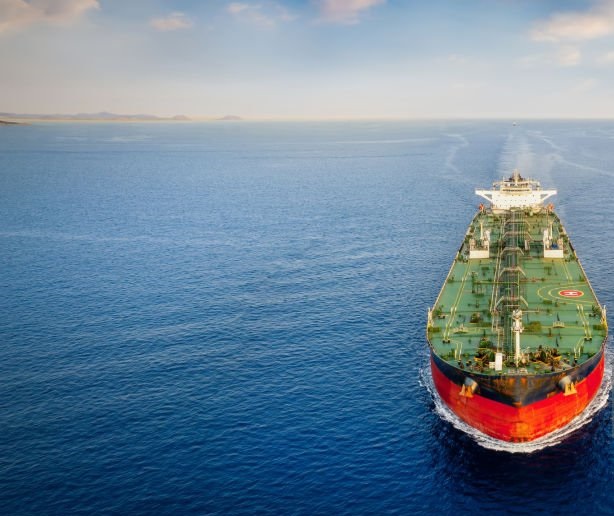 Aerial front view of a heavy crude oil tanker traveling over calm sea during sunset